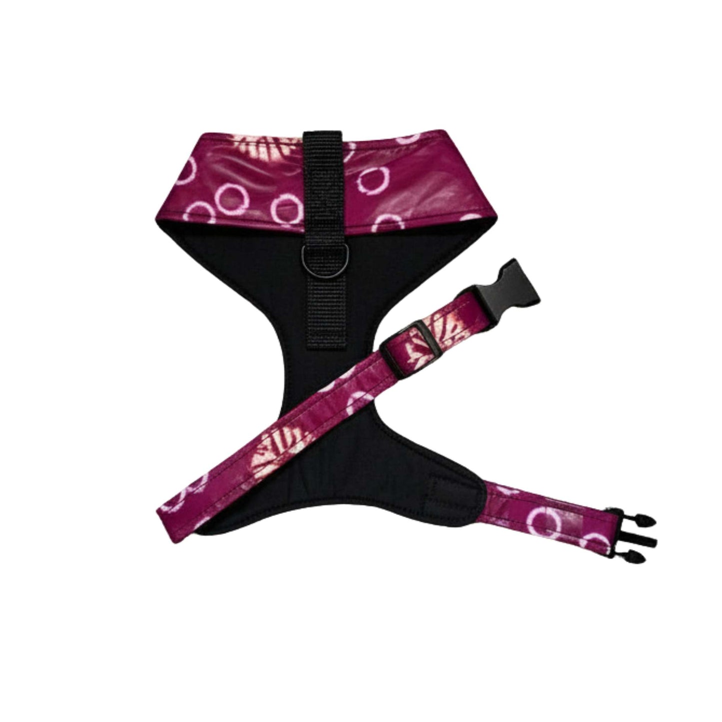 A dog harness with a black padded body and magenta-purple patterned straps featuring white circular and leaf-like motifs, shown on a plain white background.