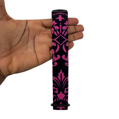 Black and pink patterned DOG COLLAR  held in a hand against a white background