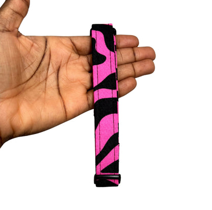 Hand holding a pink and black zebra-striped object against a white background