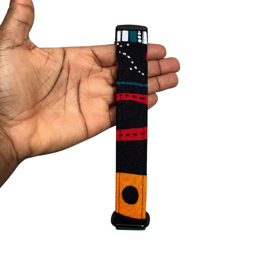Colorful dog collar  with black, red, and orange pattern held in a hand against a white background